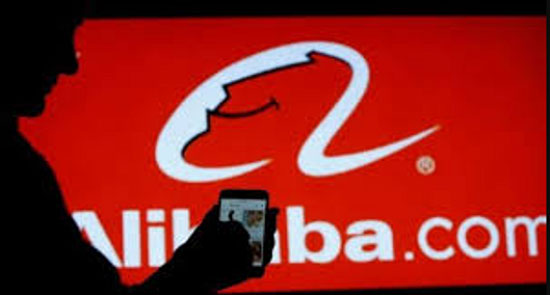 a man with phone in hand and alibaba.com logo in the background